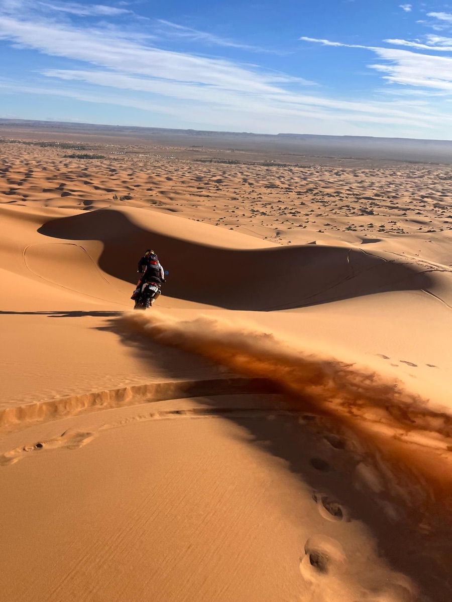 Rider cresting a sand dune on an overland desert expedition
