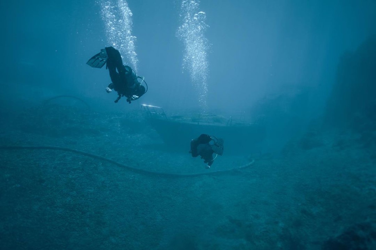 Two divers descending over a wreck on an open-water dive
